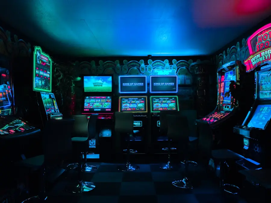 Neon-beleuchtete Spielhalle im Goblin-Dungeon mit blau, grün und magenta leuchtenden Automaten